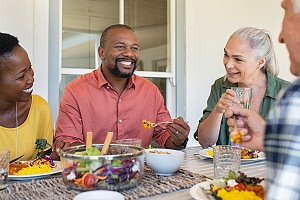 group of people sitting around table eating before Mental health therapy